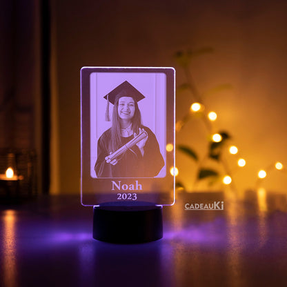 Atmosphärische LED-Fotolampe mit eingraviertem Bild des Absolventen „Noah 2023“ in violettem Licht.