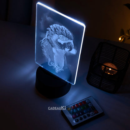 Blau beleuchtete LED-Lampe mit eingraviertem Papagei in einem dunklen Raum.