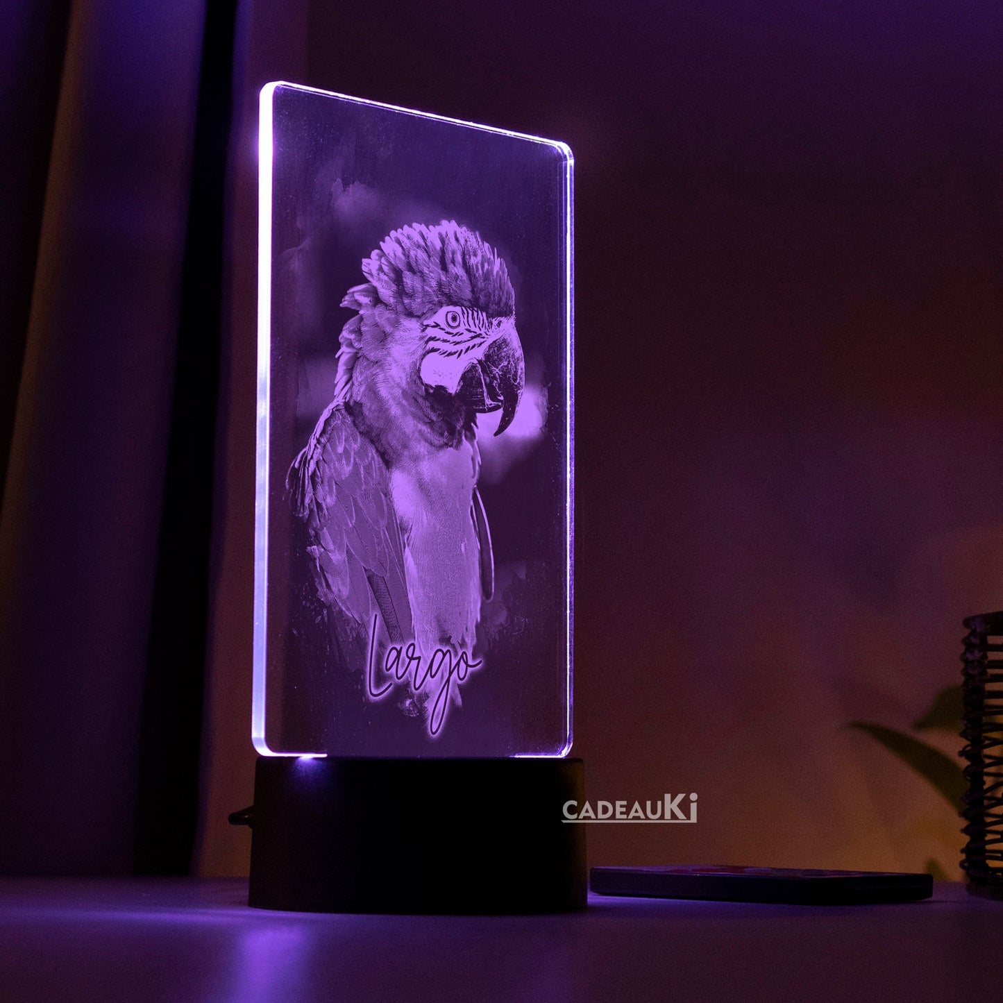 LED-Lampe in violetter Beleuchtung, die einen gravierten Papagei auf dunklem Hintergrund zeigt.