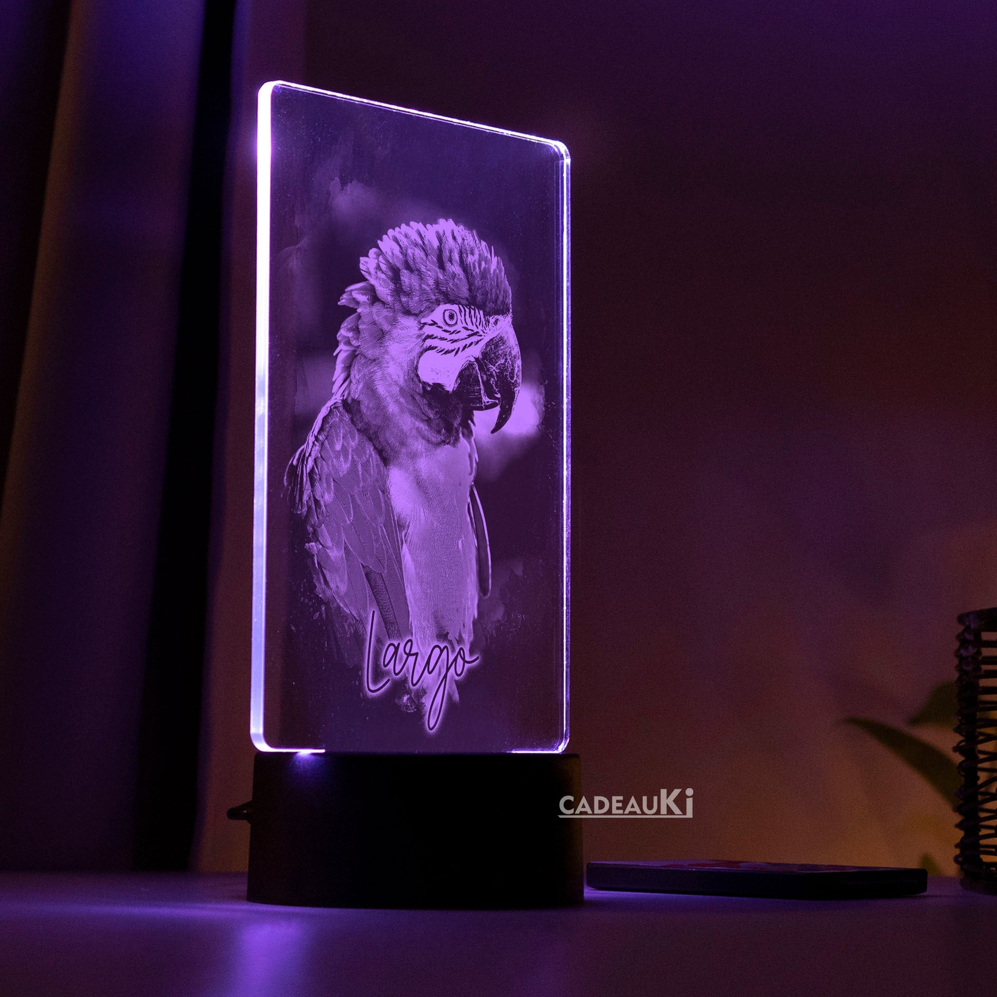 LED-Lampe in violetter Beleuchtung, die einen gravierten Papagei auf dunklem Hintergrund zeigt.
