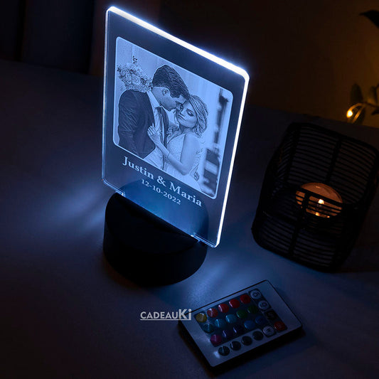 LED-Fotolampe mit persönlichem Foto und Datum, die mit blauem Licht vor dunklem Hintergrund beleuchtet wird.